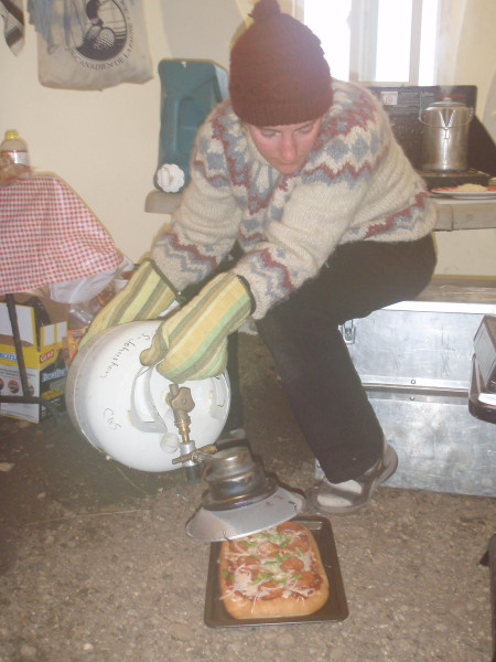 Christine Anderson finishes browning a pizza with a propane heater. Photo by Paul Woodard.