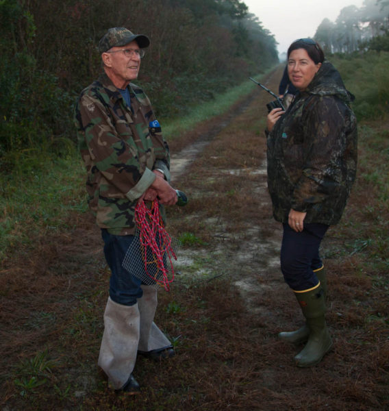 Joe Davis (left) and Lauren Mowbray (right) wait along the road to be picked up after successfully releasing woodpeckers in the swamp at dawn. Photo by Bryan Watts.